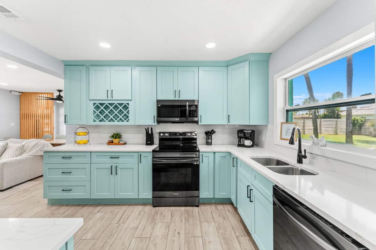 Renovated kitchen with seafoam cabinets, stone counters and stainless appliances