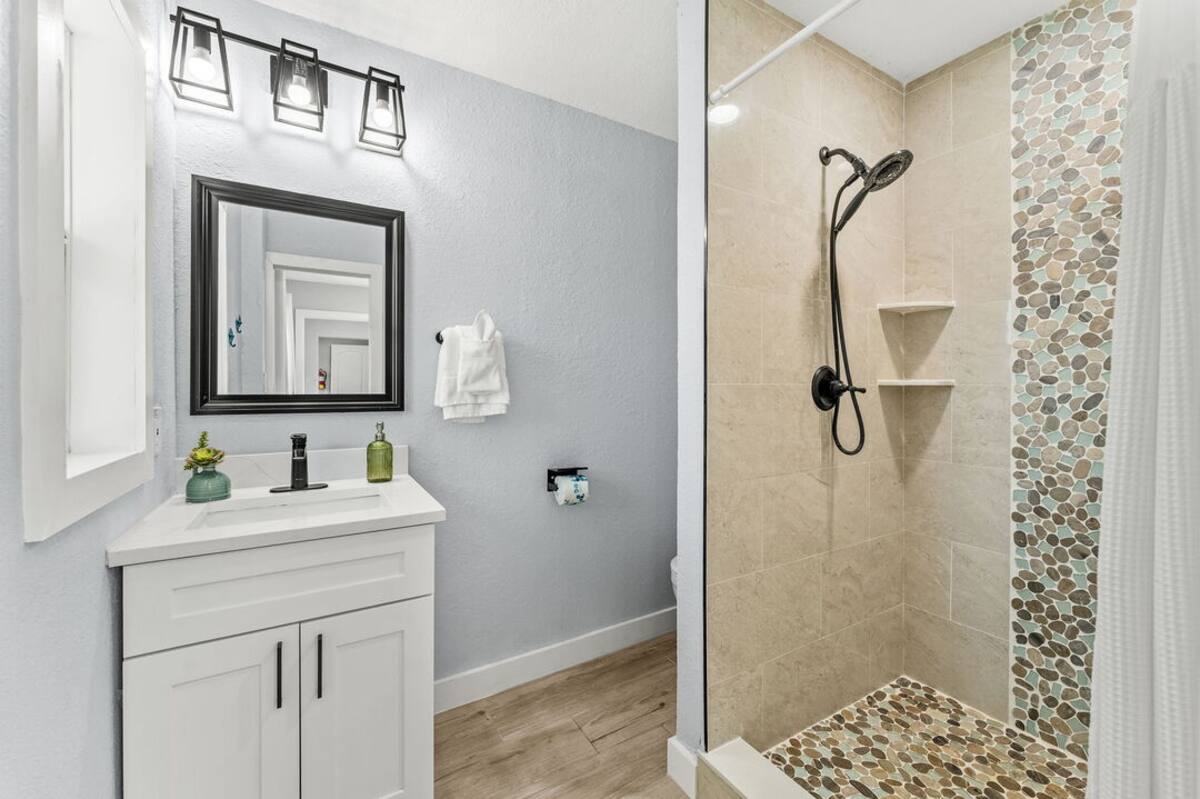Bathroom with walk-in pebble-tile shower and vanity