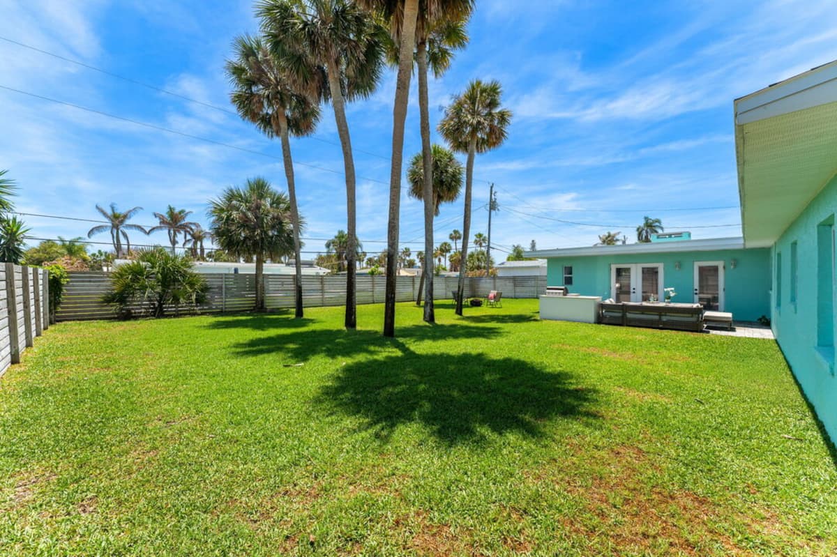 Fenced yard with mature palms and open lawn