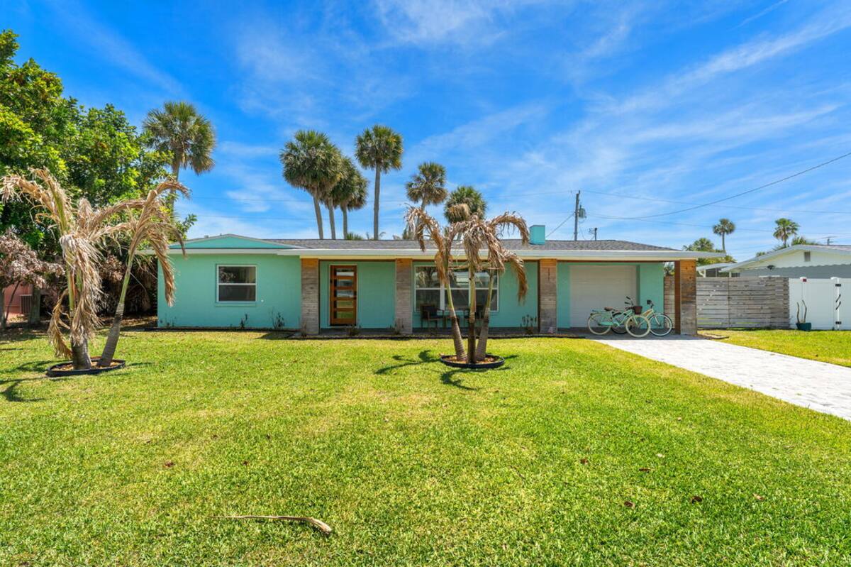 Large grassy backyard with palm trees behind the house